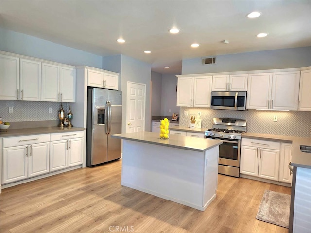 26523 Starling Ct, Canyon Country, CA 91387 - kitchen with stainless steel appliances, white cabinetry, light wood-style floors, decorative backsplash, and recessed lighting