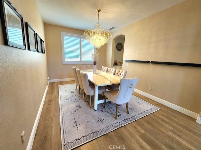 26523 Starling Ct, Canyon Country, CA 91387 - dining room with arched walkways, a chandelier, and wood finished floors