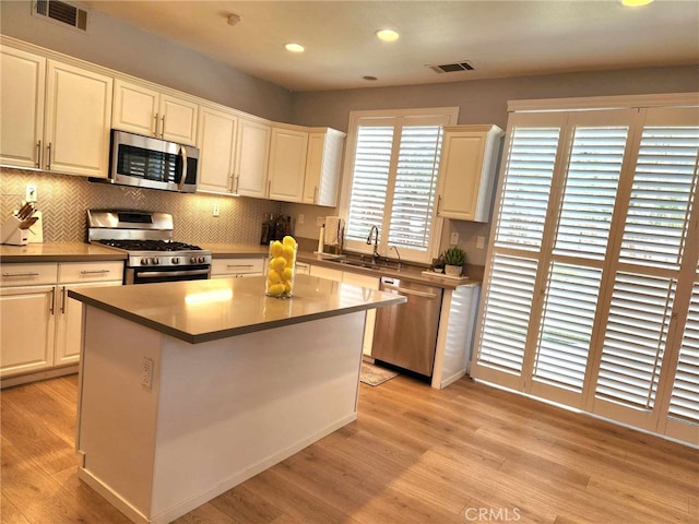 26523 Starling Ct, Canyon Country, CA 91387 - kitchen with stainless steel appliances, light wood finished floors, backsplash, a kitchen island, and recessed lighting