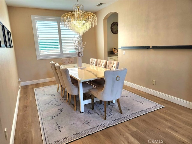 26523 Starling Ct, Canyon Country, CA 91387 - dining area with arched walkways, a chandelier, and wood finished floors