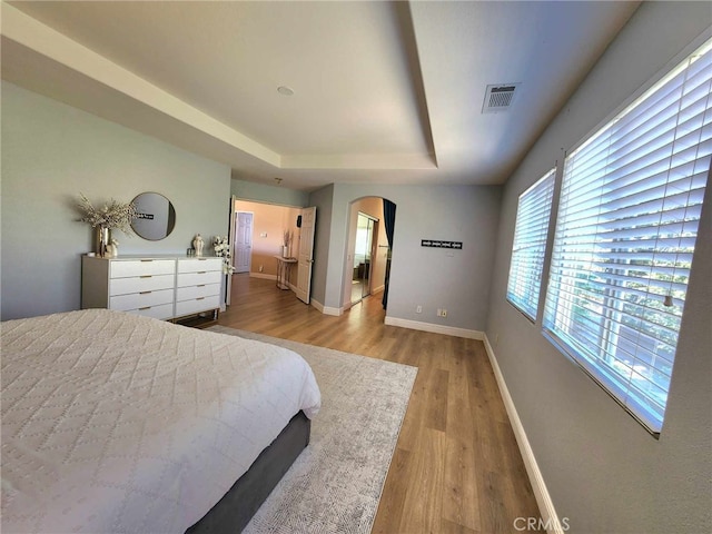 26523 Starling Ct, Canyon Country, CA 91387 - bedroom featuring arched walkways, light wood-style floors, and a raised ceiling