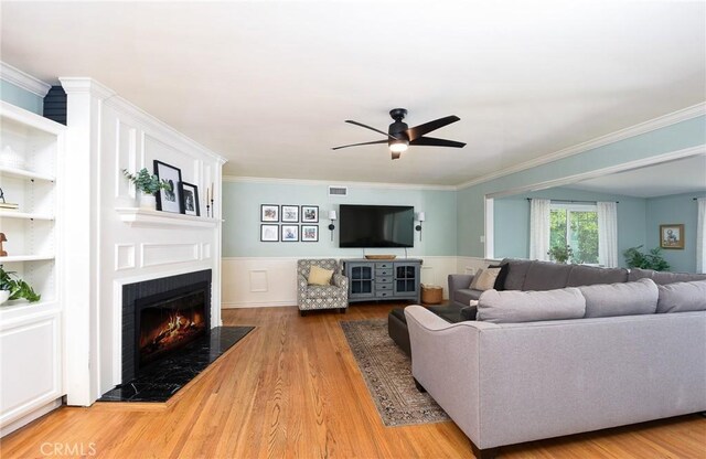 7311 Westwood Dr, Riverside, CA 92504 - living room featuring a fireplace with flush hearth, a ceiling fan, crown molding, light wood-type flooring, and wainscoting