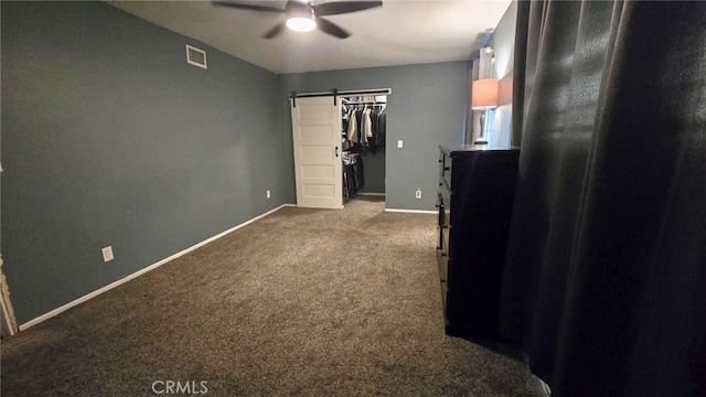 8514 Hickory Ln, Riverside, CA 92504 - unfurnished bedroom featuring a barn door, carpet flooring, a walk in closet, a ceiling fan, and a closet