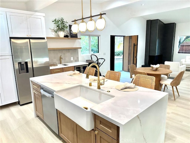 10335 Babbitt Ave, Granada Hills, CA 91344 - kitchen featuring stainless steel appliances, vaulted ceiling, light wood-style floors, tasteful backsplash, and light stone counters
