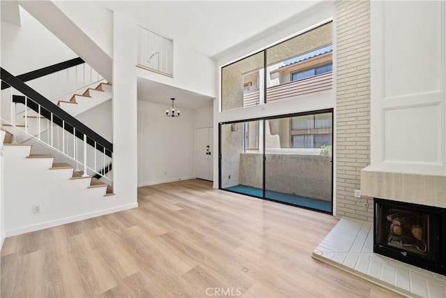 5510 Las Virgenes Rd, Calabasas, CA 91302 - unfurnished living room featuring a high ceiling, stairway, a brick fireplace, wood finished floors, and a chandelier