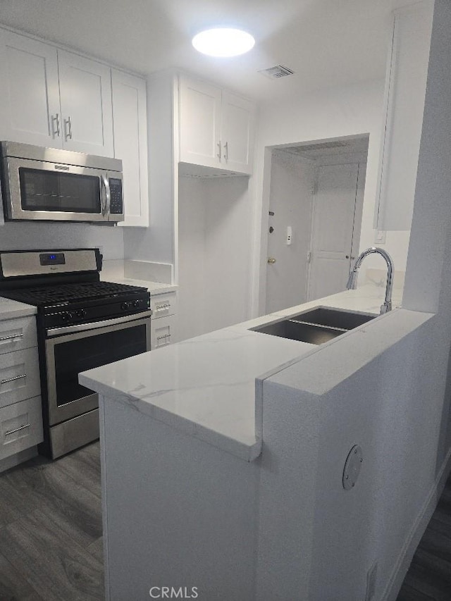 21000 Parthenia St Unit 6, Canoga Park, CA 91304 - kitchen featuring appliances with stainless steel finishes, dark wood-style floors, white cabinetry, and a peninsula