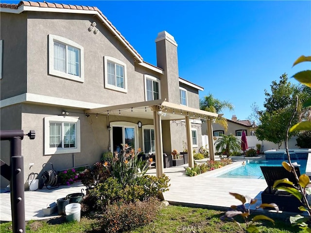 1539 Carmel Ct, Redlands, CA 92374 - back of house featuring stucco siding, a chimney, and a pool with connected hot tub