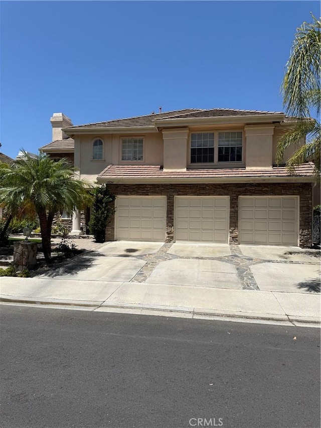 22241 Birchleaf, Mission Viejo, CA 92692 - view of front facade featuring an attached garage, stucco siding, driveway, a chimney, and stone siding