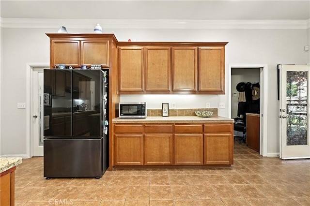 17024 Granite Falls Way, Chowchilla, CA 93610 - kitchen with smart refrigerator, stainless steel microwave, crown molding, light countertops, and brown cabinets