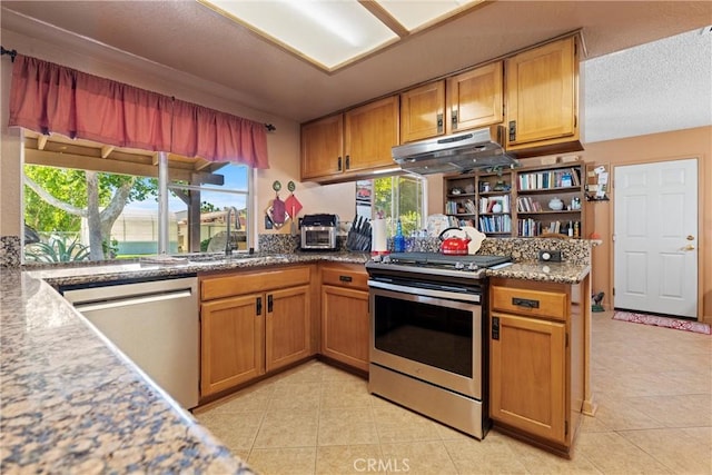 36916 95th St E, Littlerock, CA 93543 - kitchen featuring stainless steel appliances, under cabinet range hood, light tile patterned floors, and brown cabinetry