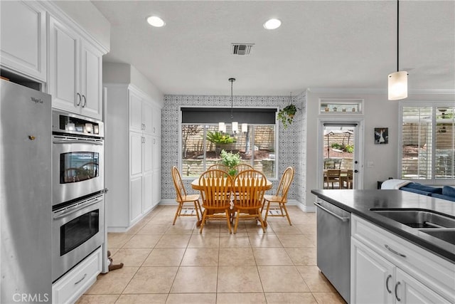 27318 Chesterfield Dr, Valencia, CA 91354 - kitchen with stainless steel appliances, wallpapered walls, white cabinets, dark countertops, and pendant lighting