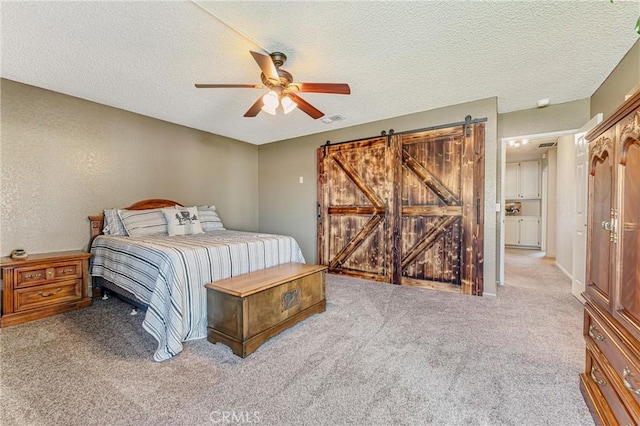 36807 95th St E, Littlerock, CA 93543 - bedroom featuring carpet floors, a textured ceiling, a barn door, and a ceiling fan