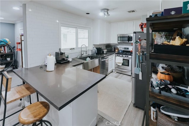 2438 Emerson Cir, Corona, CA 92882 - kitchen with stainless steel appliances, light wood-style floors, a peninsula, and white cabinets
