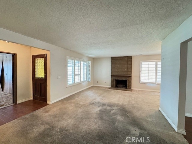 8641 Limestone Dr, Riverside, CA 92504 - unfurnished living room featuring carpet, a brick fireplace, plenty of natural light, and a textured ceiling