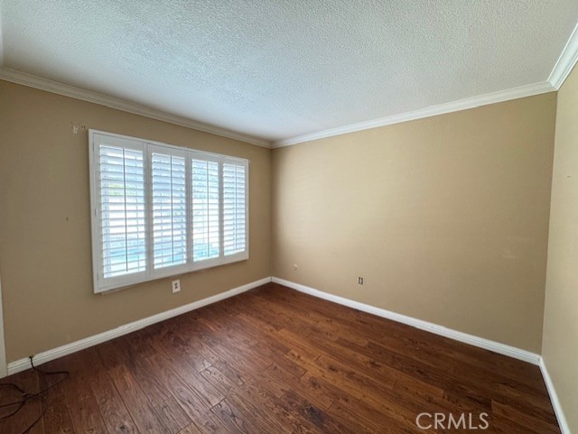 8641 Limestone Dr, Riverside, CA 92504 - empty room with dark wood finished floors, a textured ceiling, and crown molding
