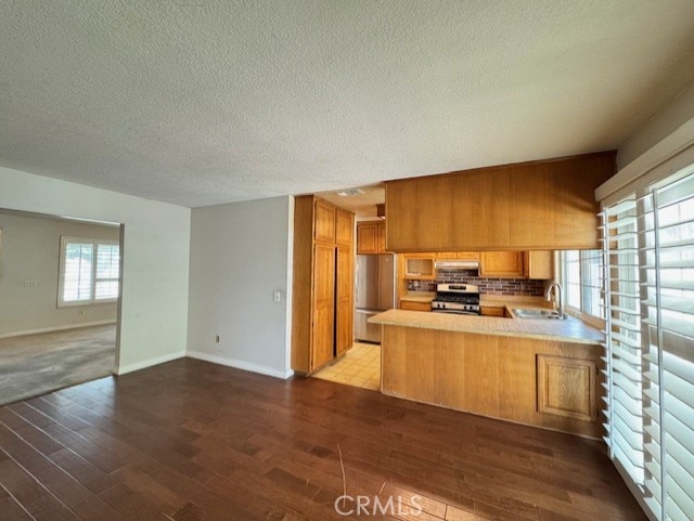 8641 Limestone Dr, Riverside, CA 92504 - kitchen featuring stainless steel appliances, open floor plan, wood finished floors, a textured ceiling, and light countertops