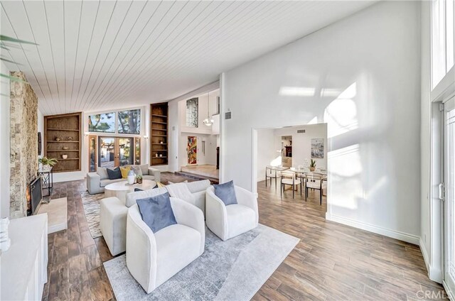 23216 Park Esperanza, Calabasas, CA 91302 - living area featuring built in features, a fireplace with raised hearth, wood ceiling, wood finished floors, and a towering ceiling