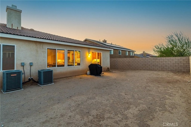 42432 72nd St W, Lancaster, CA 93536 - back of property at dusk with a fenced backyard, stucco siding, a tile roof, and a chimney