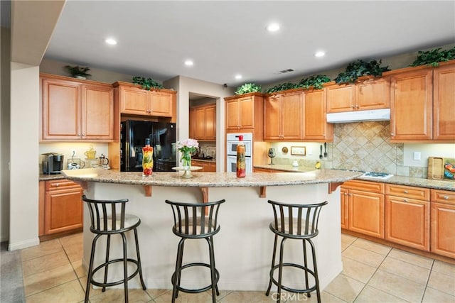 42432 72nd St W, Lancaster, CA 93536 - kitchen featuring white appliances, under cabinet range hood, a center island, a kitchen bar, and recessed lighting