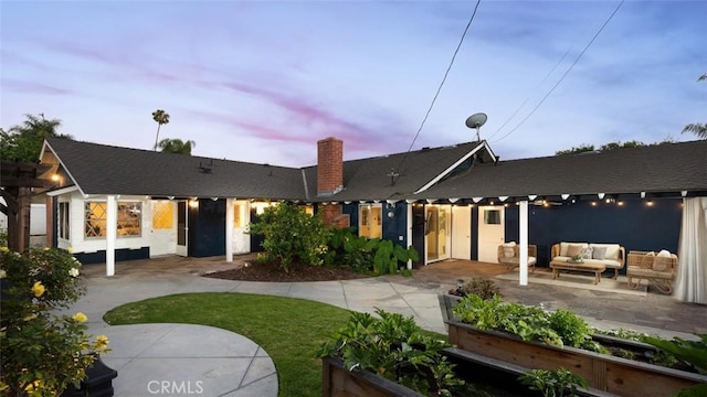 2119 E Denise Ave, Orange, CA 92867 - back of property at dusk featuring a chimney, outdoor lounge area, a garden, a patio area, and a shingled roof
