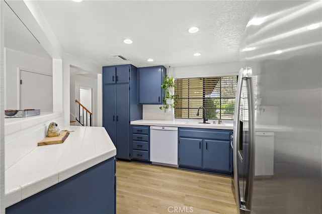 990 La Paz Rd Unit 49, Placentia, CA 92870 - kitchen featuring dishwasher, blue cabinetry, freestanding refrigerator, tile counters, and recessed lighting