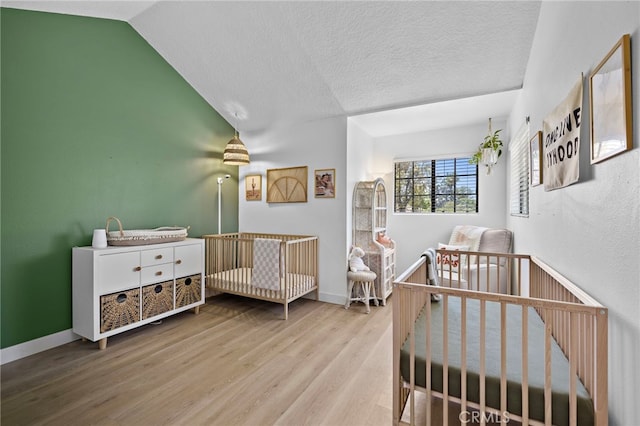 990 La Paz Rd Unit 49, Placentia, CA 92870 - bedroom featuring wood finished floors, vaulted ceiling, a textured ceiling, and a crib