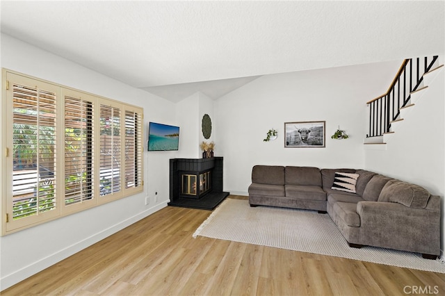 990 La Paz Rd Unit 49, Placentia, CA 92870 - living area with wood finished floors, lofted ceiling, a glass covered fireplace, and stairs