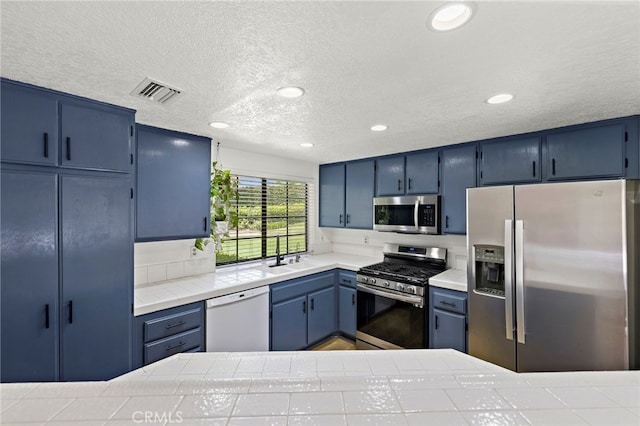 990 La Paz Rd Unit 49, Placentia, CA 92870 - kitchen with appliances with stainless steel finishes, blue cabinets, a textured ceiling, recessed lighting, and tile counters