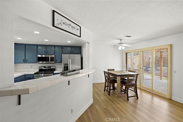 990 La Paz Rd Unit 49, Placentia, CA 92870 - kitchen featuring appliances with stainless steel finishes, blue cabinets, light wood-type flooring, a textured ceiling, and ceiling fan
