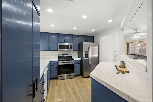 990 La Paz Rd Unit 49, Placentia, CA 92870 - kitchen featuring stainless steel appliances, blue cabinets, light wood finished floors, tile counters, and recessed lighting