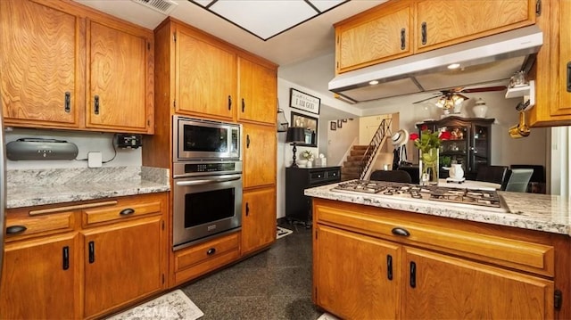 8356 Bella Vista Dr, Rancho Cucamonga, CA 91701 - kitchen featuring appliances with stainless steel finishes, a ceiling fan, brown cabinets, granite floors, and under cabinet range hood