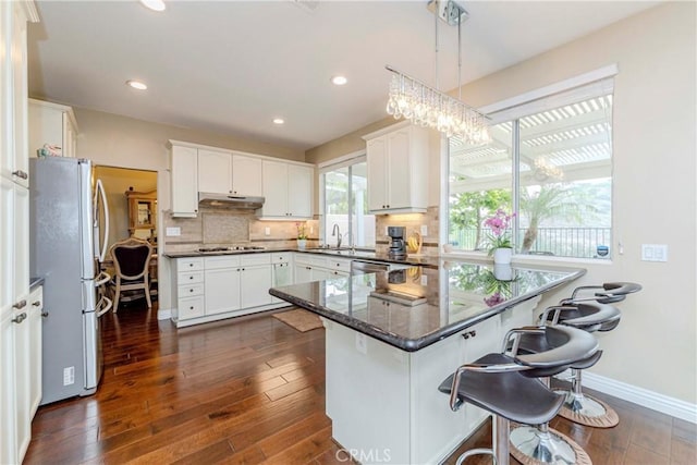 6242 E Inverness Pl, Orange, CA 92869 - kitchen with under cabinet range hood, freestanding refrigerator, a peninsula, backsplash, and white cabinets