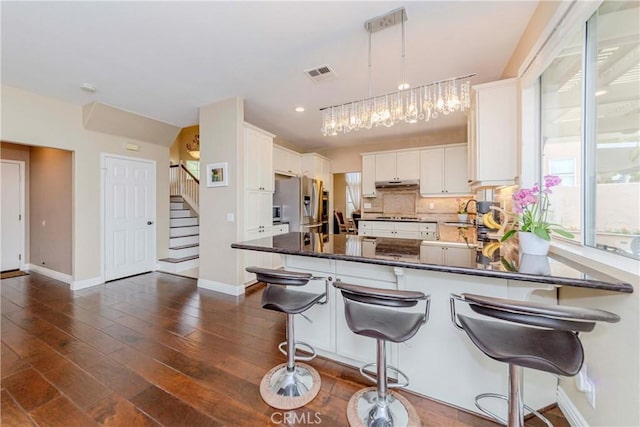 6242 E Inverness Pl, Orange, CA 92869 - kitchen featuring stainless steel refrigerator with ice dispenser, under cabinet range hood, a peninsula, recessed lighting, and dark countertops
