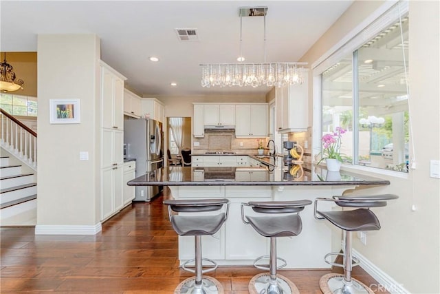 6242 E Inverness Pl, Orange, CA 92869 - kitchen with stainless steel fridge with ice dispenser, a chandelier, a peninsula, dark countertops, and dark wood finished floors