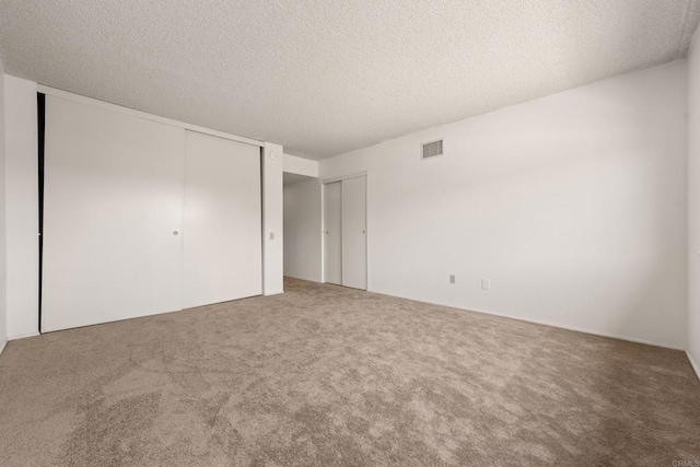 16566 Caminito Vecinos Unit 31, San Diego, CA 92128 - unfurnished bedroom featuring carpet, a textured ceiling, and multiple closets