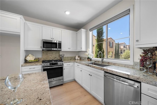 18309 Goldbark Way, Yorba Linda, CA 92886 - kitchen featuring appliances with stainless steel finishes, white cabinetry, light wood finished floors, light stone countertops, and tasteful backsplash