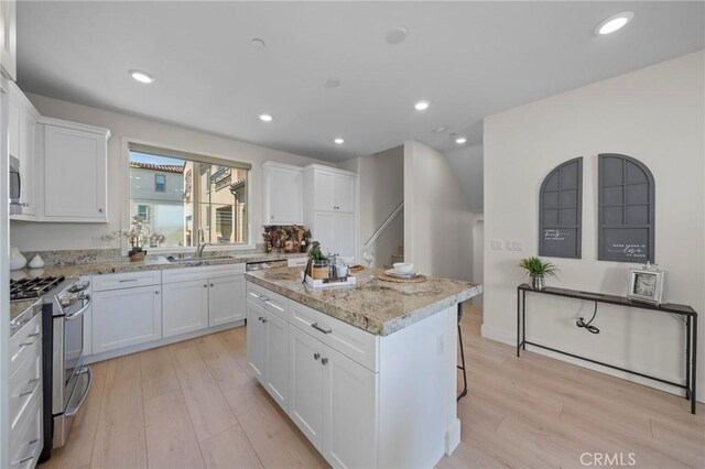 18309 Goldbark Way, Yorba Linda, CA 92886 - kitchen with stainless steel range with gas stovetop, white cabinetry, light wood-style flooring, a center island, and recessed lighting
