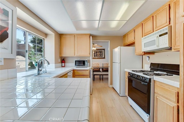 5575 Osborne Ct, San Bernardino, CA 92407 - kitchen with range with gas cooktop, white microwave, stainless steel microwave, tile counters, and light brown cabinets