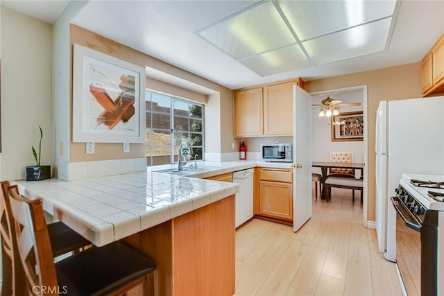 5575 Osborne Ct, San Bernardino, CA 92407 - kitchen featuring stainless steel microwave, white dishwasher, gas range oven, a peninsula, and light brown cabinets