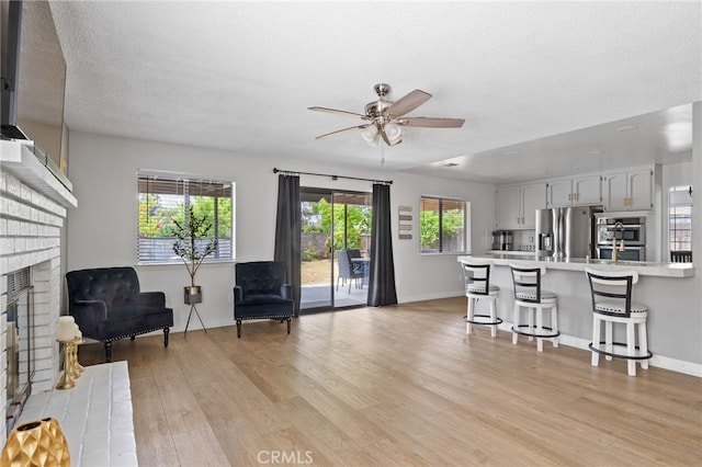 7209 Copper Creek Way, Bakersfield, CA 93308 - living area with a fireplace, ceiling fan, light wood-style flooring, and a textured ceiling