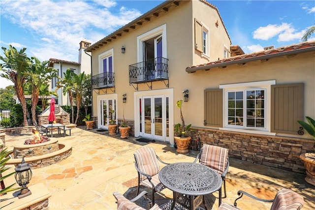 41 Balcony, Irvine, CA 92603 - rear view of house with french doors, an outdoor fire pit, a balcony, a patio, and stone siding