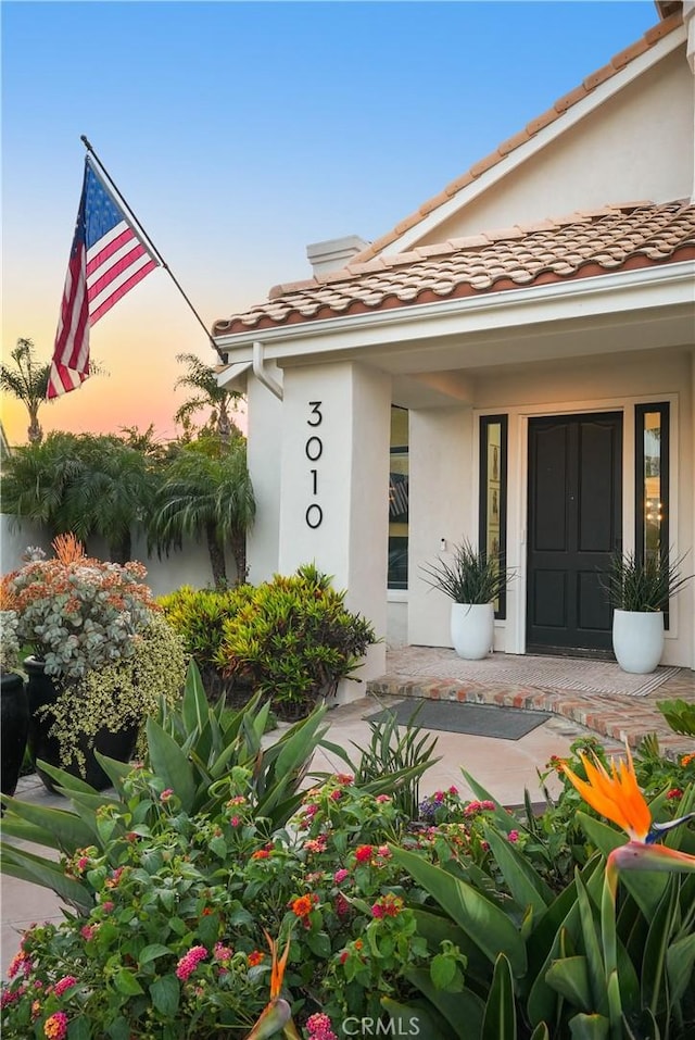 3010 Vina Vial, San Clemente, CA 92673 - exterior entry at dusk featuring stucco siding, a porch, and a tiled roof