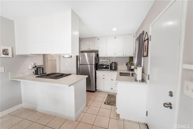 14020 Orizaba Ave Unit 6A, Paramount, CA 90723 - kitchen with stainless steel appliances, a peninsula, light countertops, light tile patterned floors, and white cabinets