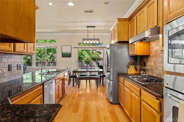 1968 Bancroft Dr, Chico, CA 95928 - kitchen with stainless steel appliances, under cabinet range hood, brown cabinets, ornamental molding, and backsplash