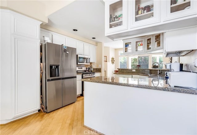 100 Stoney, Laguna Niguel, CA 92677 - kitchen with stainless steel appliances, white cabinetry, a peninsula, dark stone countertops, and light wood-style flooring