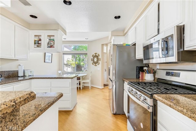 100 Stoney, Laguna Niguel, CA 92677 - kitchen with appliances with stainless steel finishes, light wood-style flooring, white cabinetry, light stone counters, and glass insert cabinets