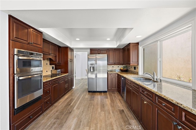 24191 Vis D Oro, Dana Point, CA 92629 - kitchen with appliances with stainless steel finishes, light wood-style flooring, a raised ceiling, tasteful backsplash, and light stone countertops
