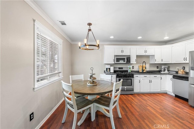 43249 42nd St W, Lancaster, CA 93536 - kitchen with appliances with stainless steel finishes, dark countertops, a chandelier, white cabinets, and ornamental molding