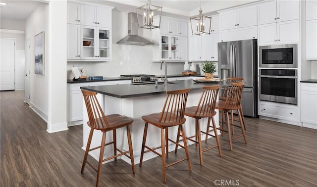 233 Carmelita Ln, Tehachapi, CA 93561 - kitchen featuring stainless steel appliances, wall chimney range hood, dark countertops, dark wood-style flooring, and white cabinetry