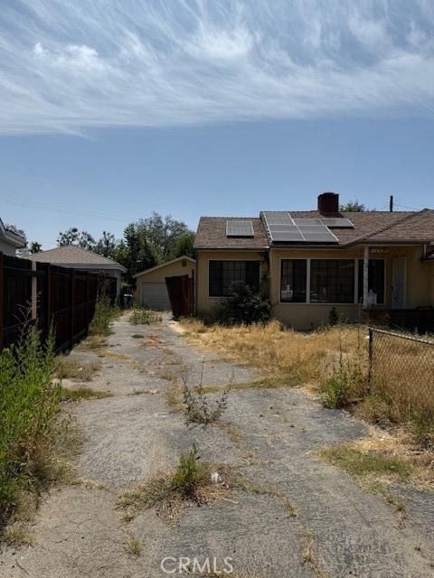 14594 Dyer St, Sylmar, CA 91342 - view of front facade with roof mounted solar panels, a chimney, asphalt driveway, and an attached garage